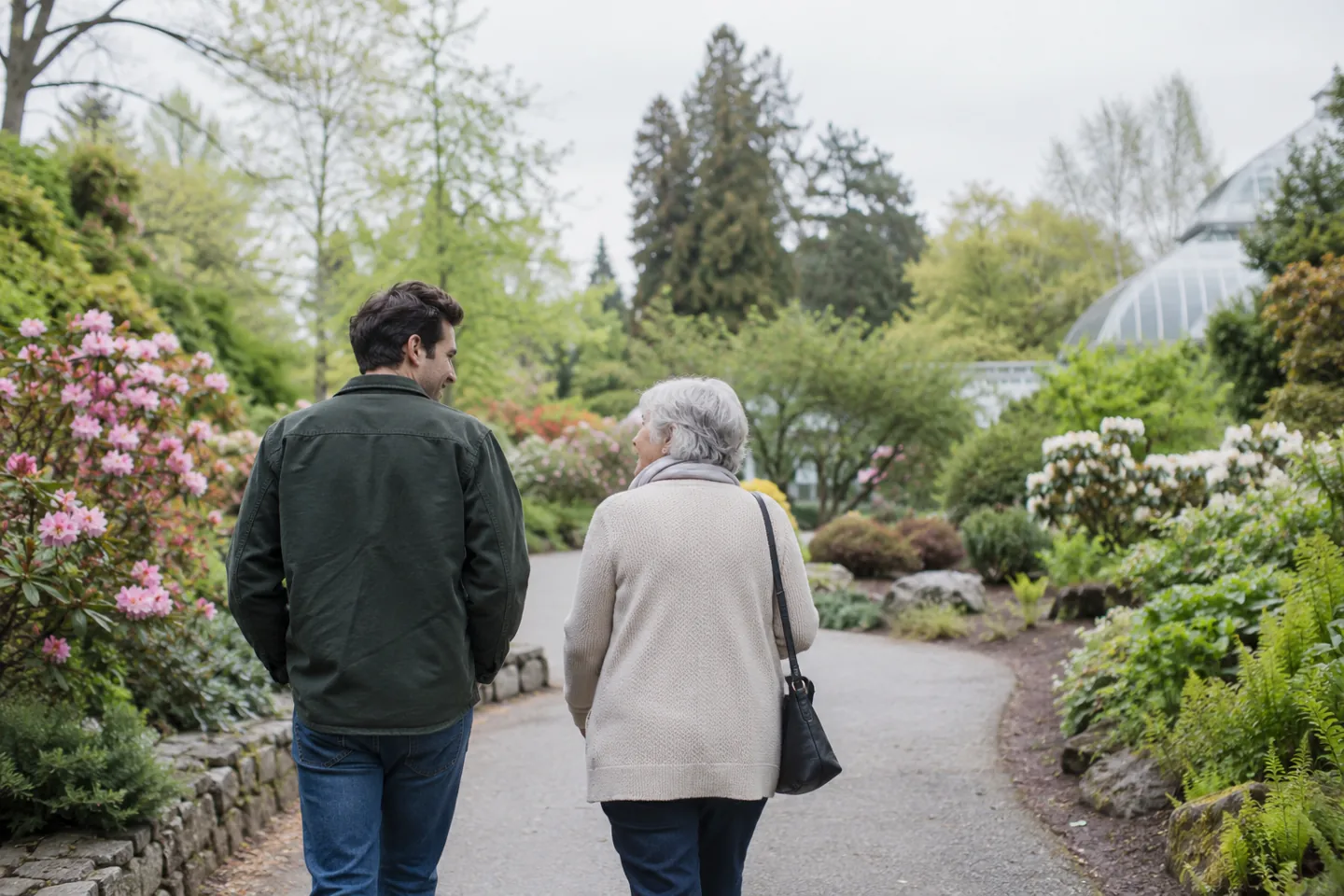 Mother and adult son walking together along a leafy path